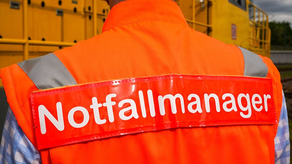 Mann trägt orangefarbene Weste mit der Aufschrift "Notfallmanager"